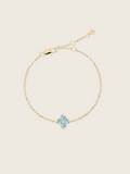 A flatlay of the mini crystal hydrangea necklace with a blue crystal flower, showcasing it's sparkle on a neutral background 