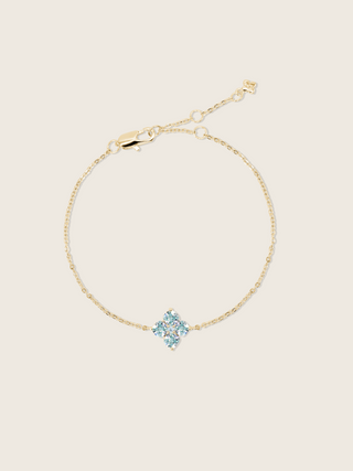 A flatlay of the mini crystal hydrangea necklace with a blue crystal flower, showcasing it's sparkle on a neutral background 