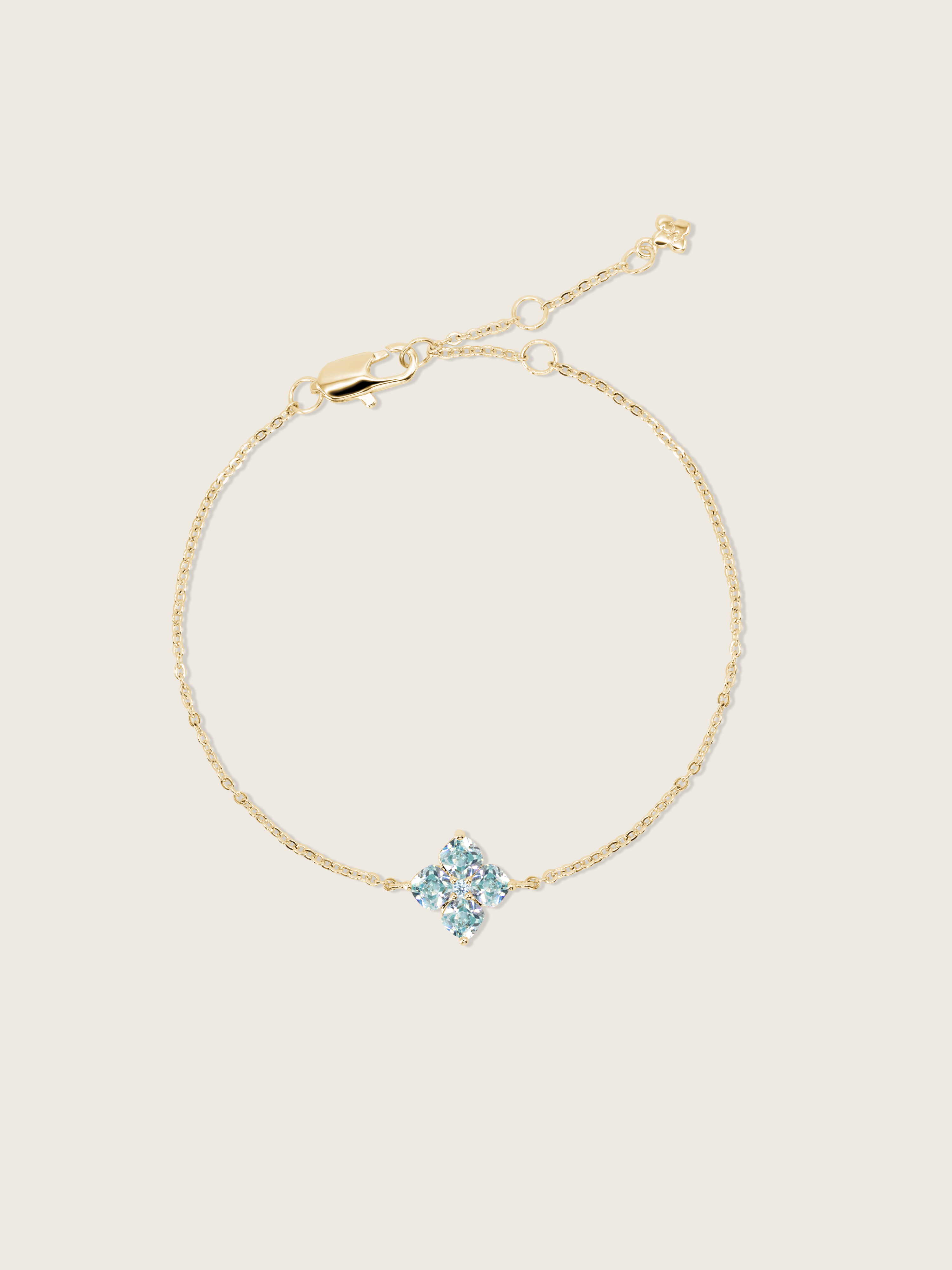 A flatlay of the mini crystal hydrangea necklace with a blue crystal flower, showcasing it's sparkle on a neutral background 