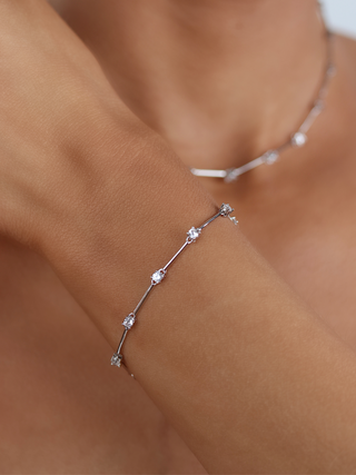 Model wearing Astra Bracelet in white gold plated brass with cubic zirconia bar and stone design, dainty wrist jewellery with matching necklace