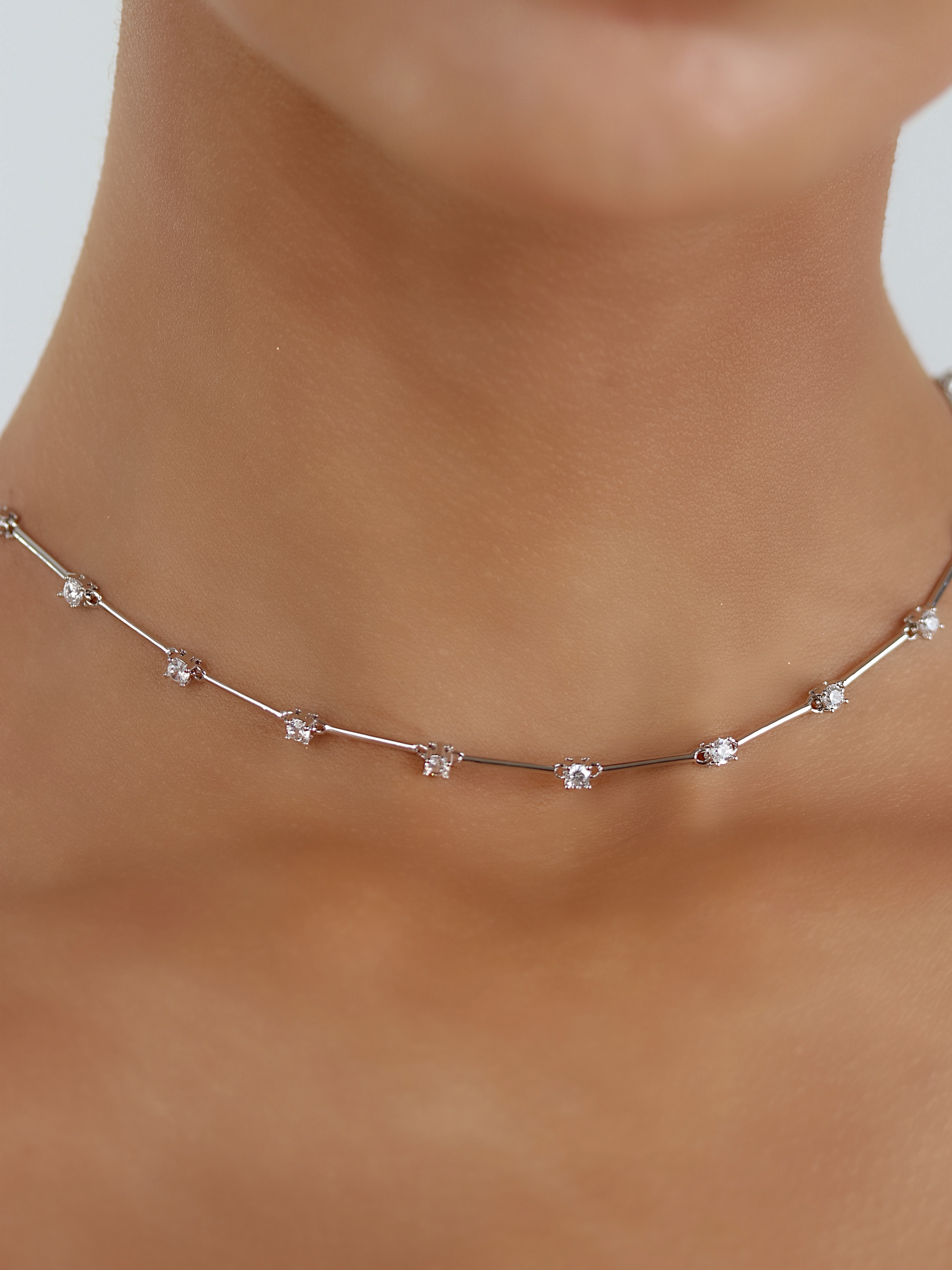 Astra necklace with premium white gold plating and cubic zirconia stars, close up on neckline
