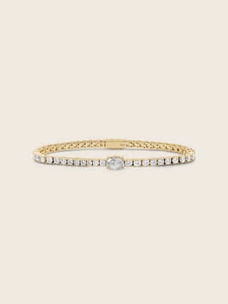 Aurelia 14k gold plated tennis bracelet with central oval clear CZ stone and classic flatlay on neutral background