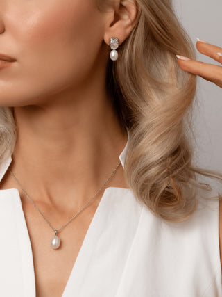 Model wearing Aurelia earrings with clear oval CZ stones and freshwater pearls, paired with the Audrey white gold plated pearl pendant necklace