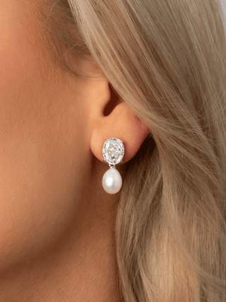 Close-up of Aurelia earring featuring clear oval CZ stone and freshwater pearl drop in premium white gold plating