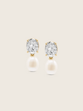 Flatlay of Aurelia earrings with clear CZ stones and freshwater pearl drops in 14k gold plating on neutral background