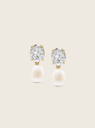 Flatlay of Aurelia earrings with clear CZ stones and freshwater pearl drops in 14k gold plating on neutral background