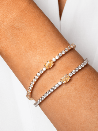 Close-up of model wearing two Aurelia lemon drop tennis bracelets with yellow oval CZ stones, one gold plated and one white gold plated