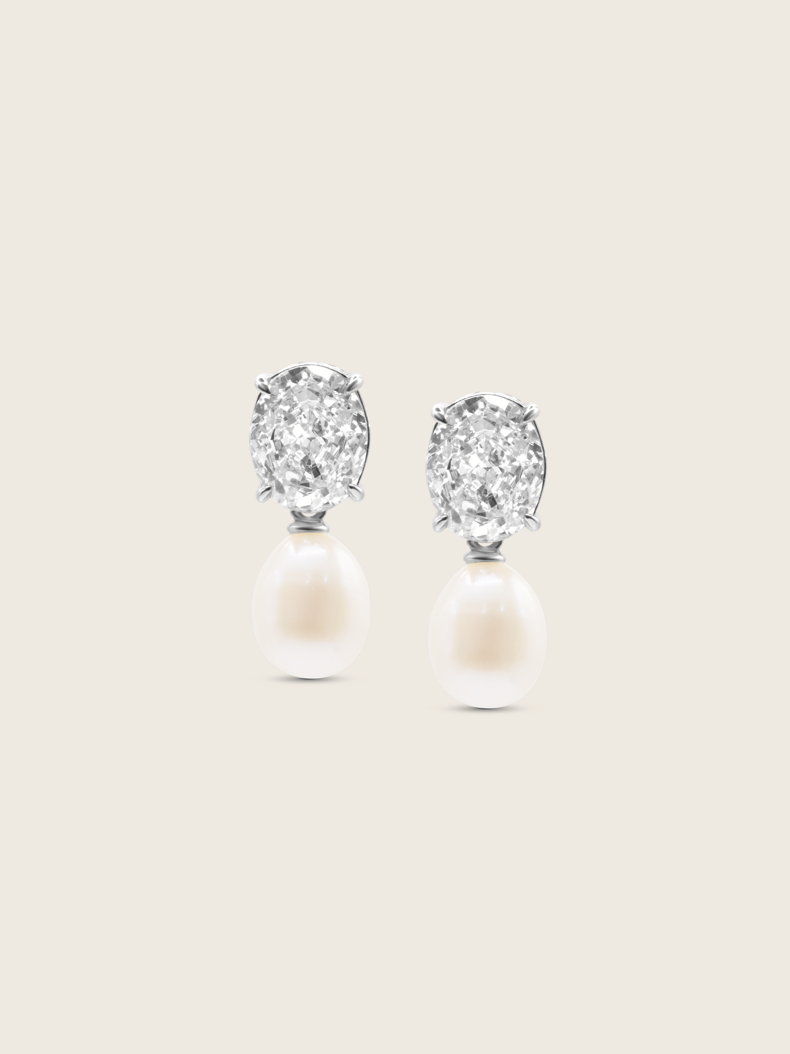 Aurelia earrings with oval clear CZ stones and freshwater pearl drops in premium white gold plating, displayed on a neutral background