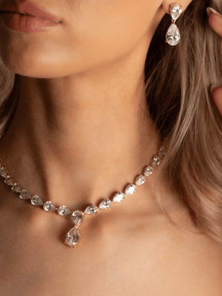 Close up of Aurora Necklace and Earrings in 14k gold plating with pear cut cubic zirconia, worn together as a statement jewellery set
