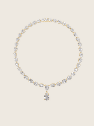 Flatlay of the Aurora Necklace with pear shaped cubic zirconia stones on a fine 14k gold plated chain, displayed on a neutral background