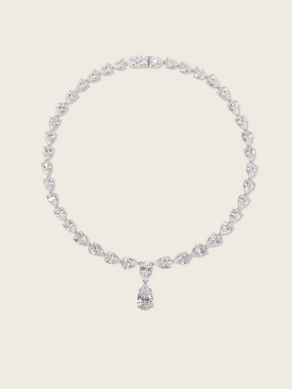 Flatlay of the Aurora Necklace in premium white gold plating with pear cut cubic zirconia stones, displayed on a neutral background
