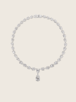 Flatlay of the Aurora Necklace in premium white gold plating with pear cut cubic zirconia stones, displayed on a neutral background