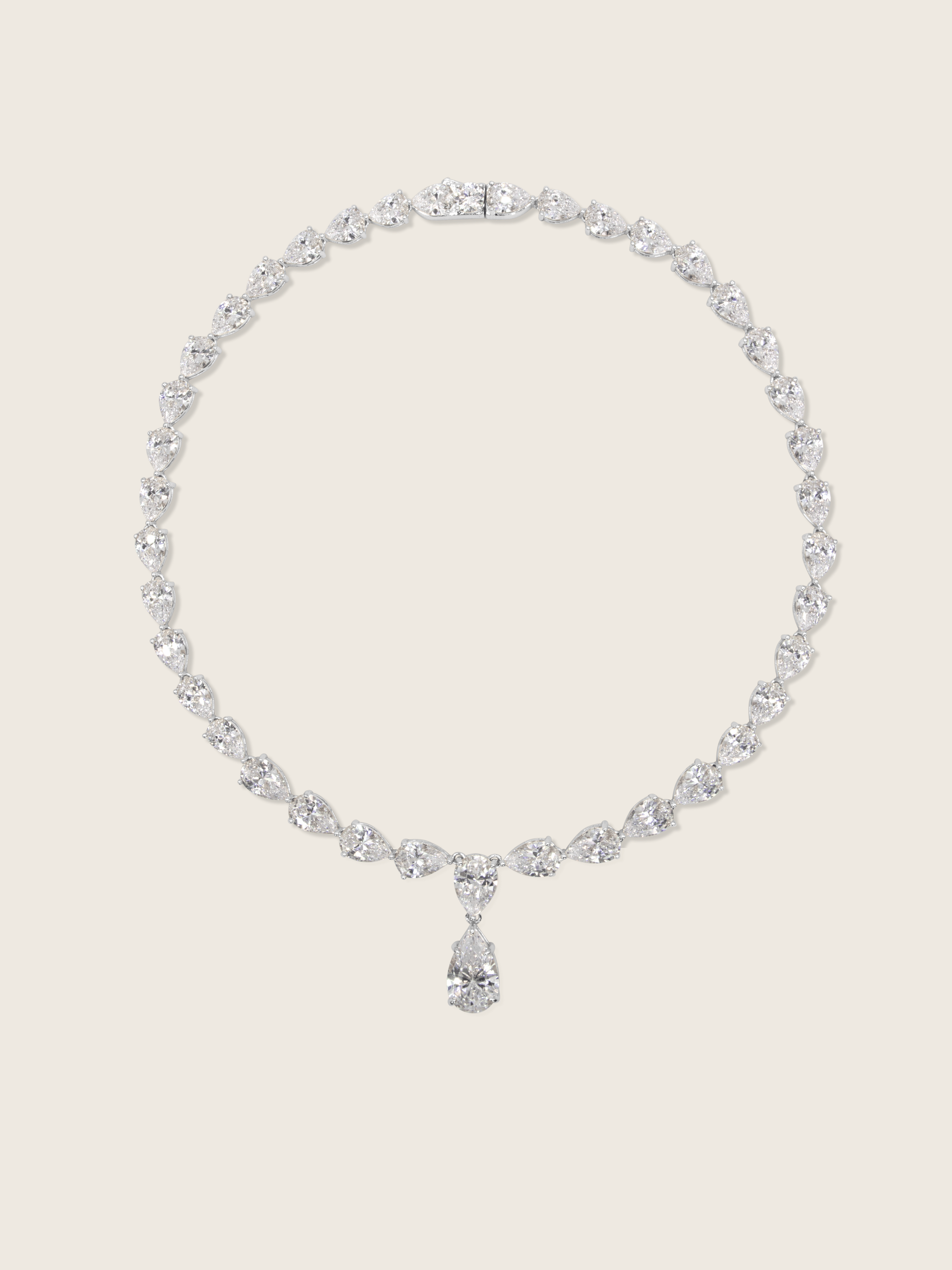 Flatlay of the Aurora Necklace in premium white gold plating with pear cut cubic zirconia stones, displayed on a neutral background