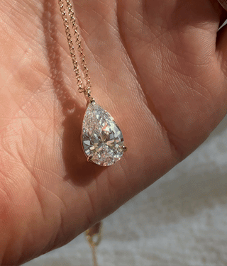 Aurora Pendant Necklace in 14k gold plating with pear shaped cubic zirconia, shown sparkling in sunlight close up