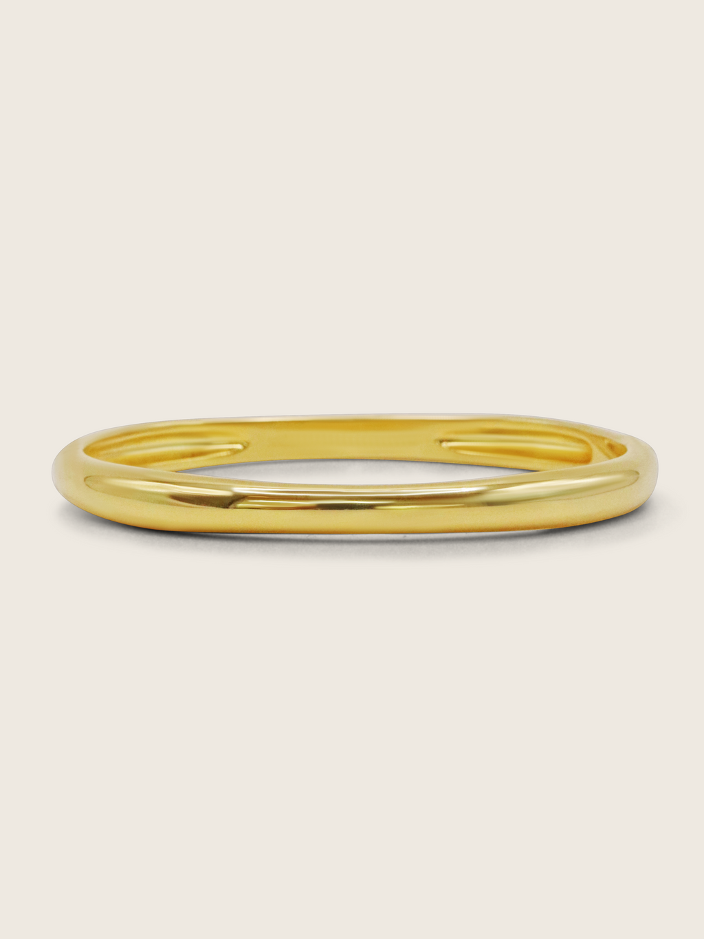 Christy bangle in 14k gold plating with smooth, polished finish on neutral background