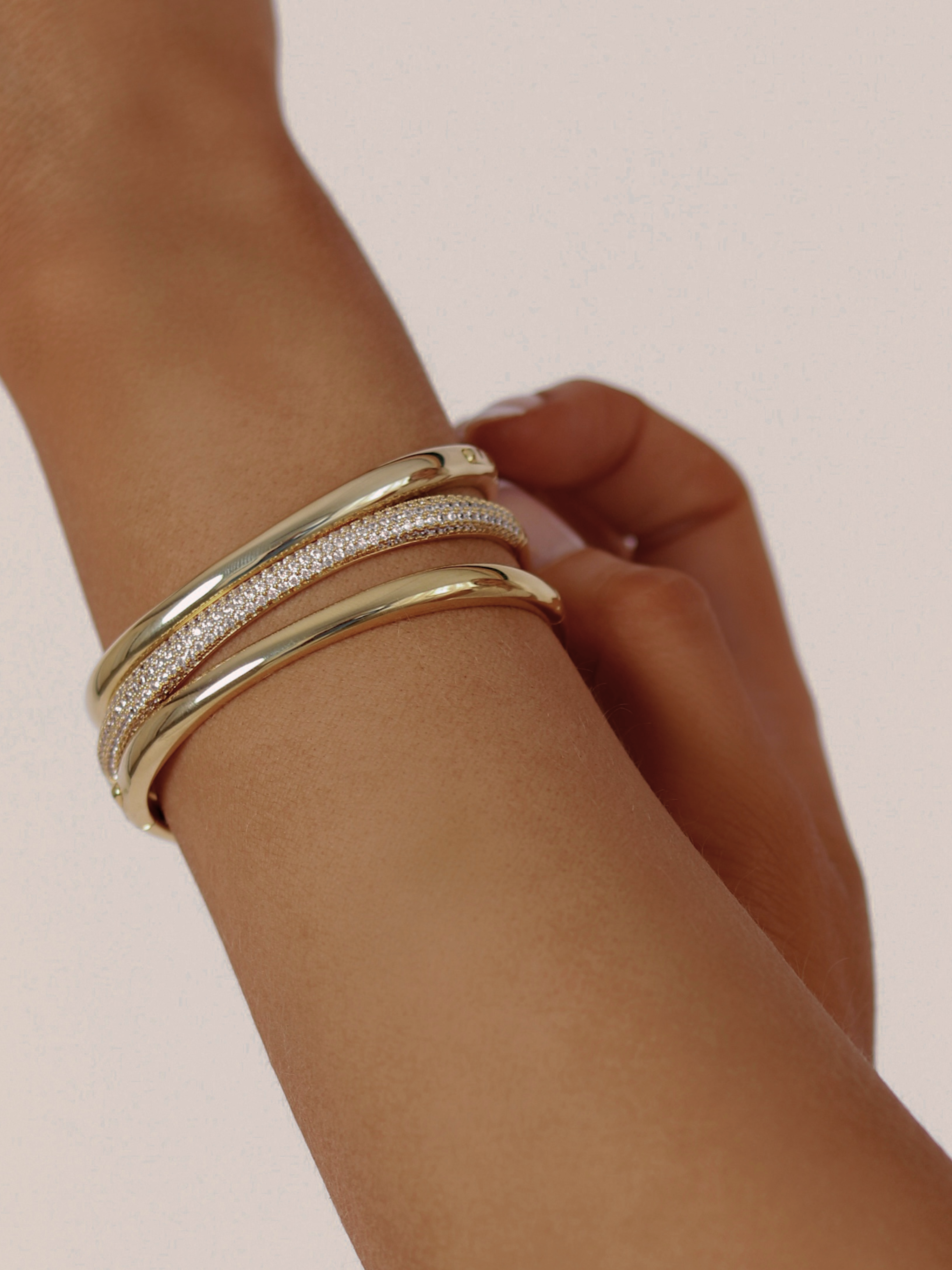 Christy pavé bangle in gold styled with two smooth gold Christy bangles, worn stacked on wrist