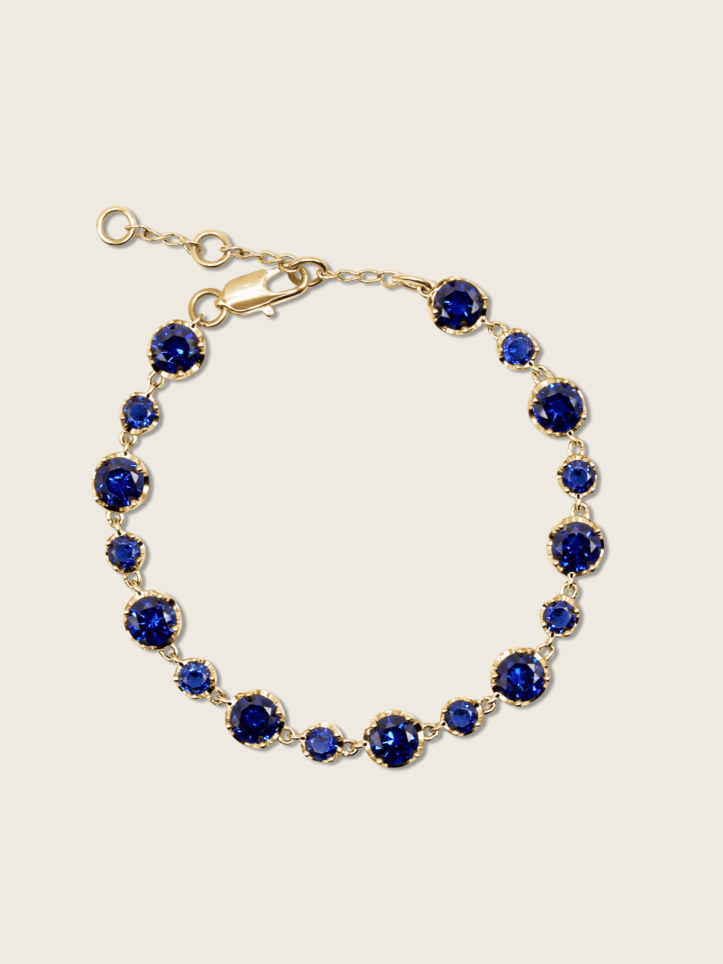 Clarissa Bracelet in 14k gold plating with deep blue cubic zirconia stones in graduated sizes, displayed on neutral background