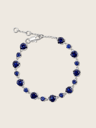 Clarissa white gold plated bracelet with round navy blue cubic zirconia stones in a graduated tennis design, elegant fine jewellery for women, shown on a white background.
