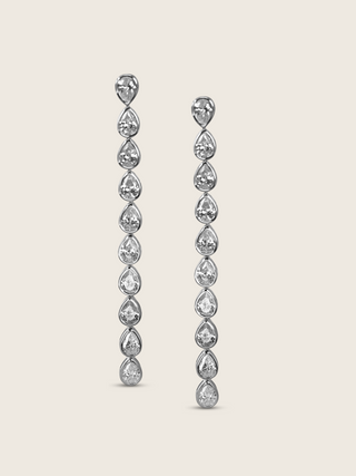 Constance drop earrings featuring a vertical row of pear-shaped cubic zirconia stones set in white gold plated sterling silver, elegant dangle design on neutral background.