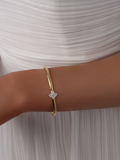 Close-up of the Crystal Hydrangea Bangle on a model’s wrist, paired with a white dress, showcasing the sparkling hydrangea stone set on a gold-plated bangle.