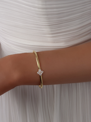 Close-up of the Crystal Hydrangea Bangle on a model’s wrist, paired with a white dress, showcasing the sparkling hydrangea stone set on a gold-plated bangle.