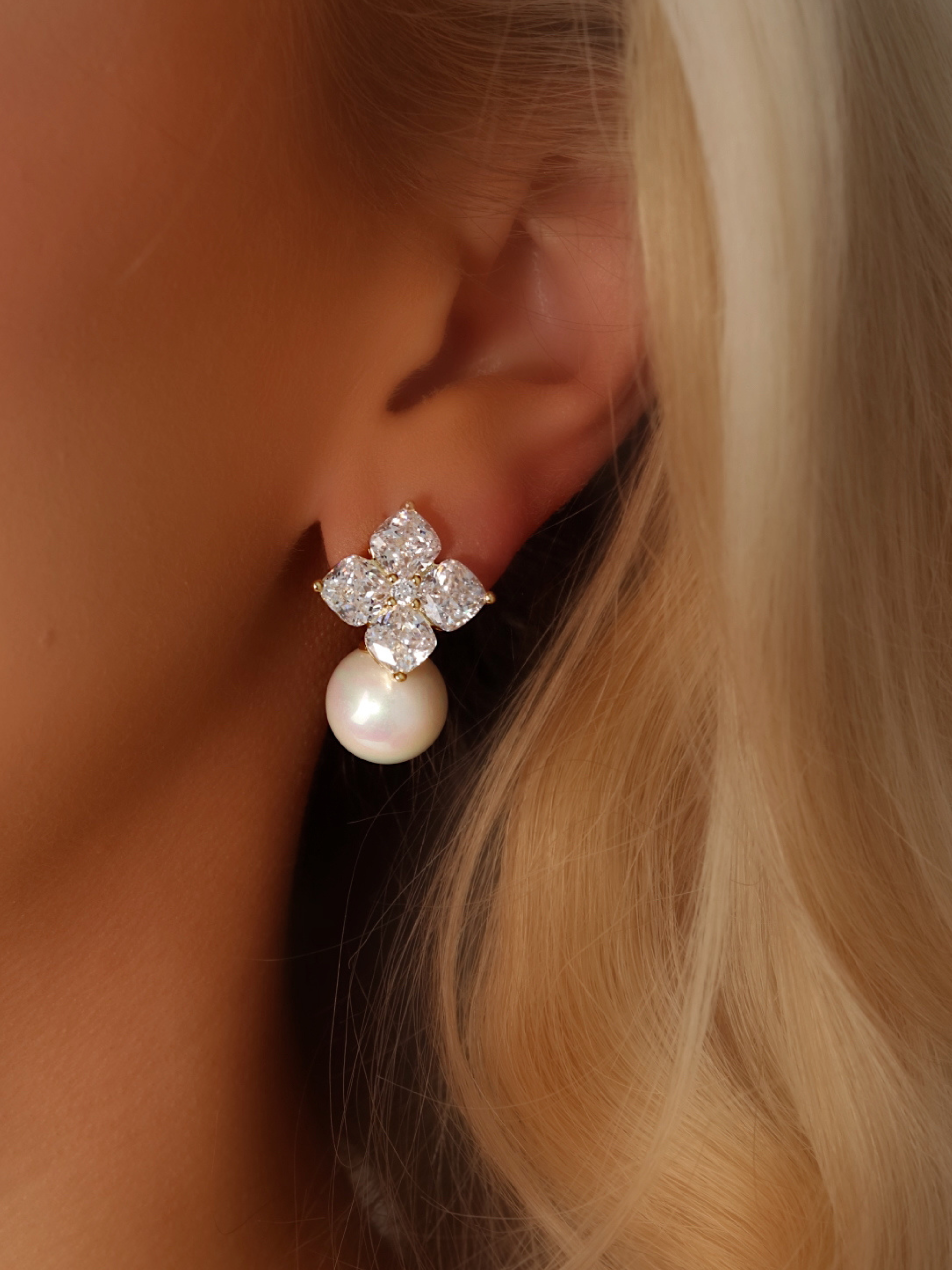 Close-up of a model wearing the Crystal Hydrangea Earrings with Shell Pearl, showing the radiant CZ floral top and the elegant shell pearl drop in a gold-plated sterling silver setting.