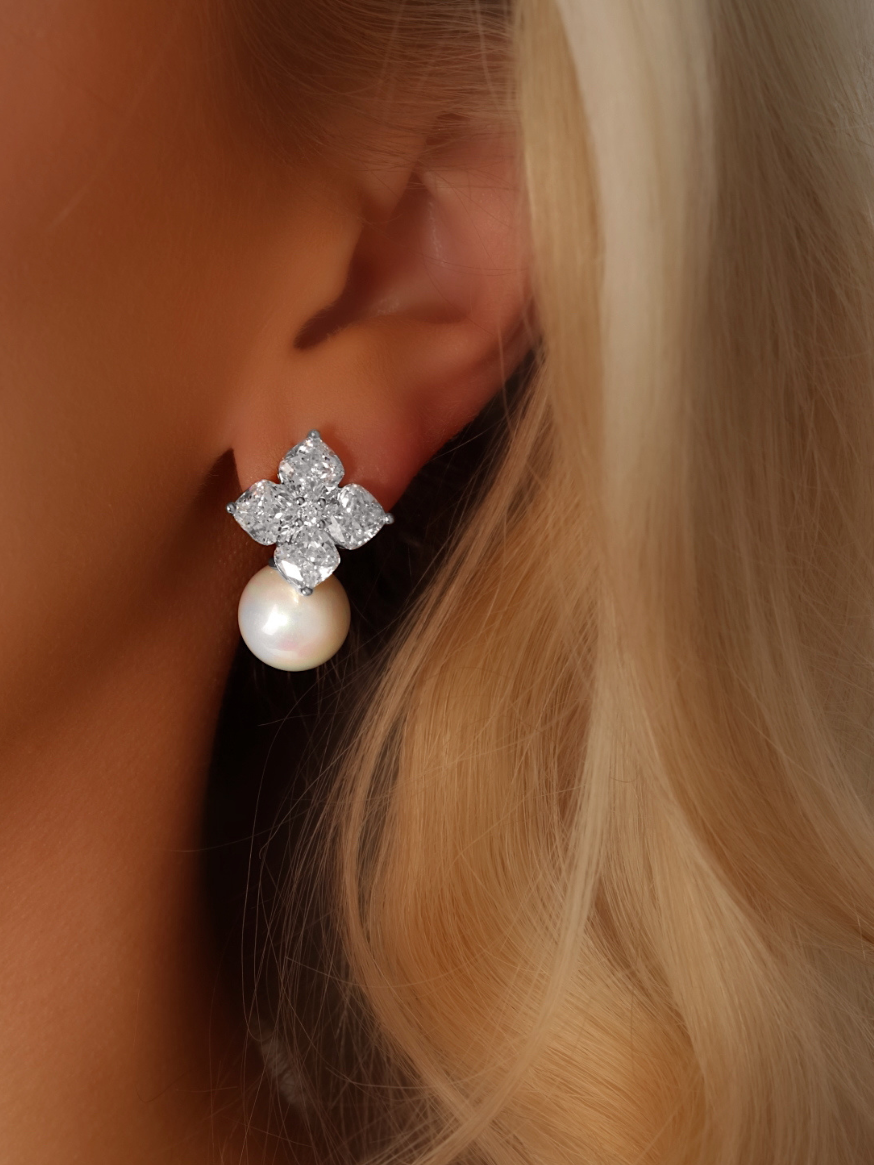 Close-up of a model wearing the Crystal Hydrangea Earrings with Shell Pearl, showing the radiant CZ floral top and the elegant shell pearl drop in a white gold-plated sterling silver setting.