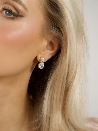 close-up of model wearing gold plated Elodie earrings, with a neutral white background