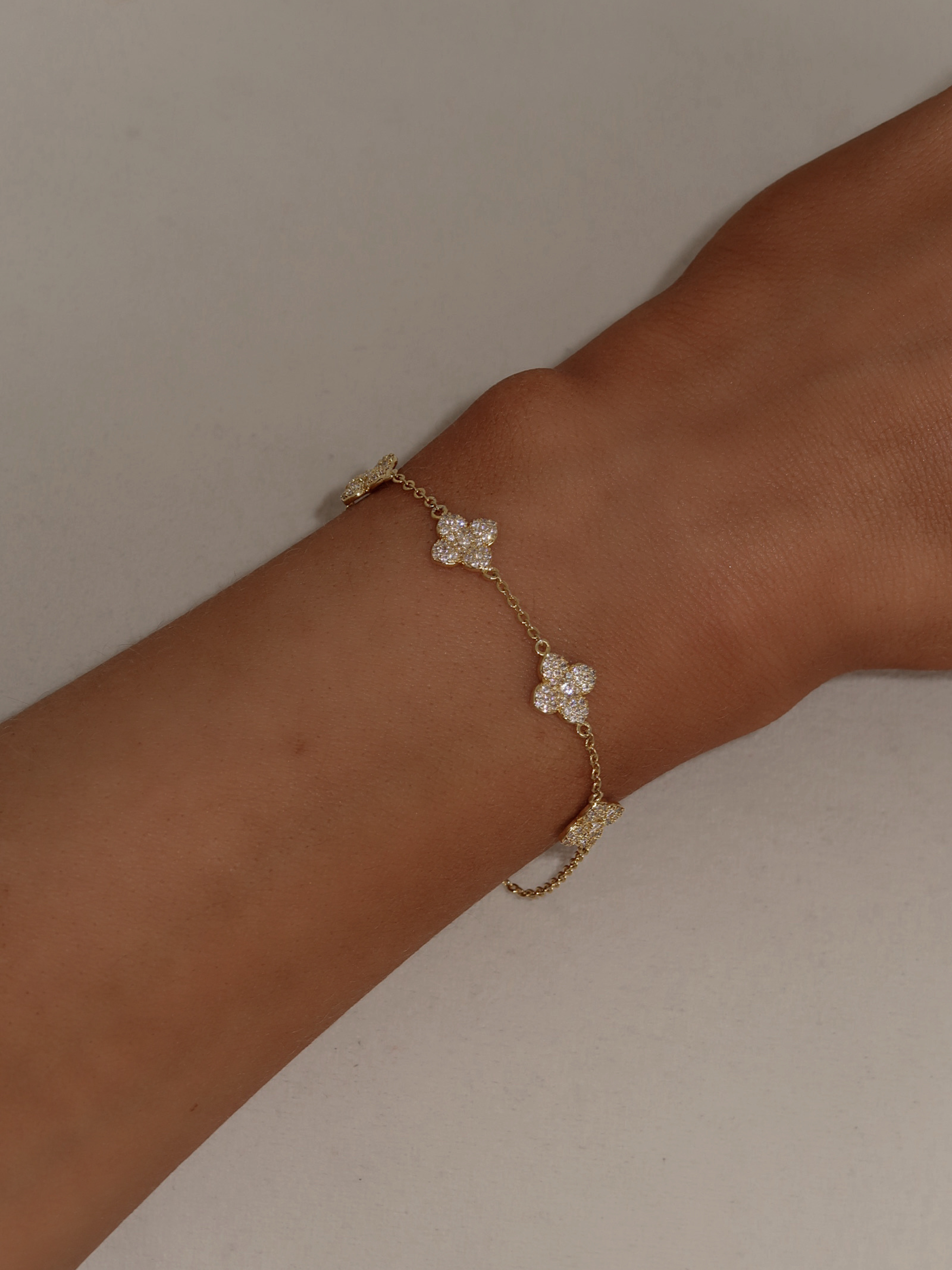 Top view of gold Multi Mini Hydrangea bracelet styled on wrist against a soft neutral background