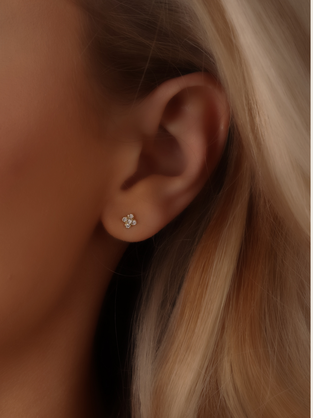 Close-up of gold plated micro hydrangea pavé earrings, small stud design on model’s ear, featuring delicate hydrangea-inspired details and sparkling pavé crystals, offering a luxurious yet affordable look.