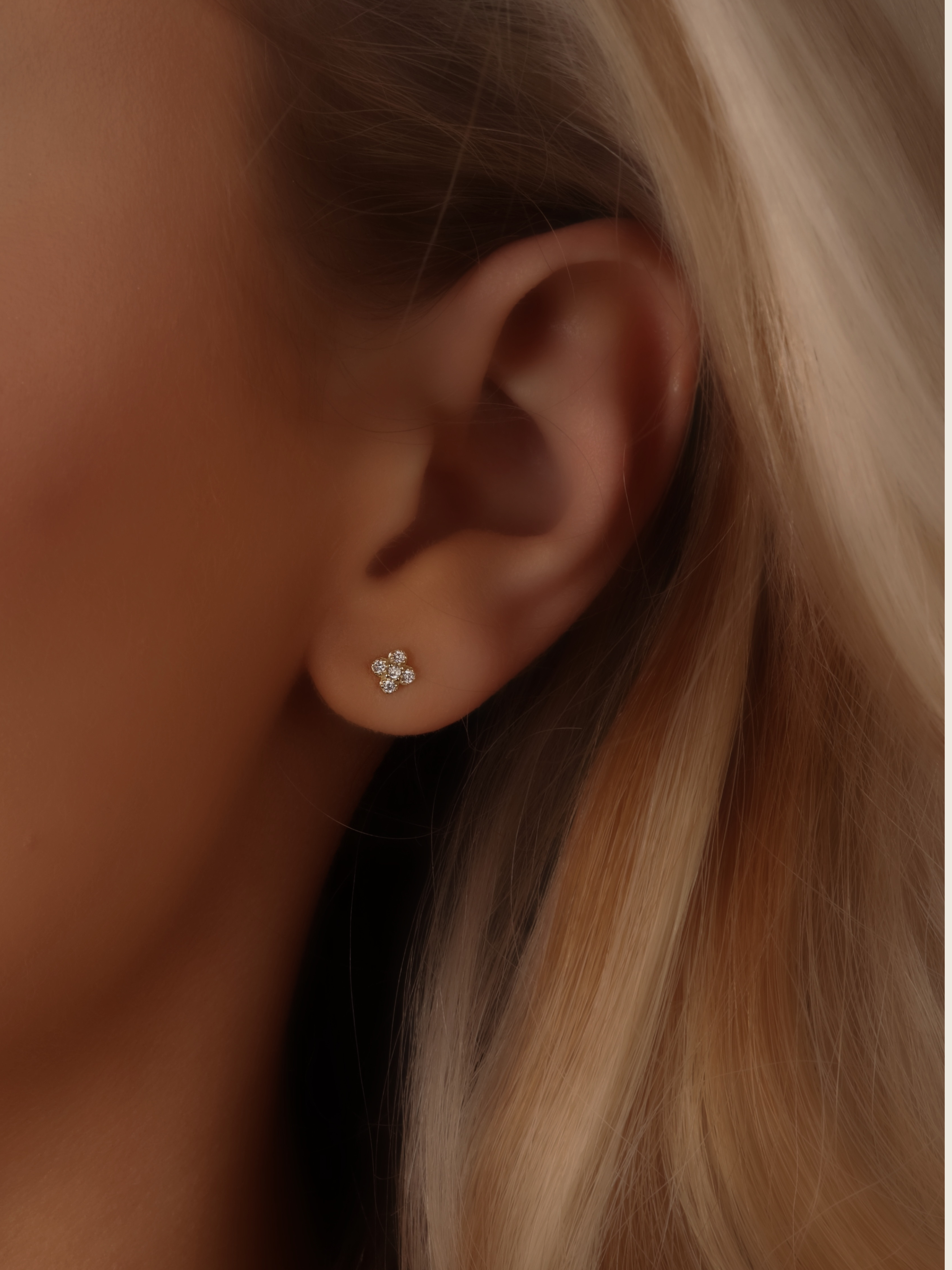 Close-up of gold plated micro hydrangea pavé earrings, small stud design on model’s ear, featuring delicate hydrangea-inspired details and sparkling pavé crystals, offering a luxurious yet affordable look.