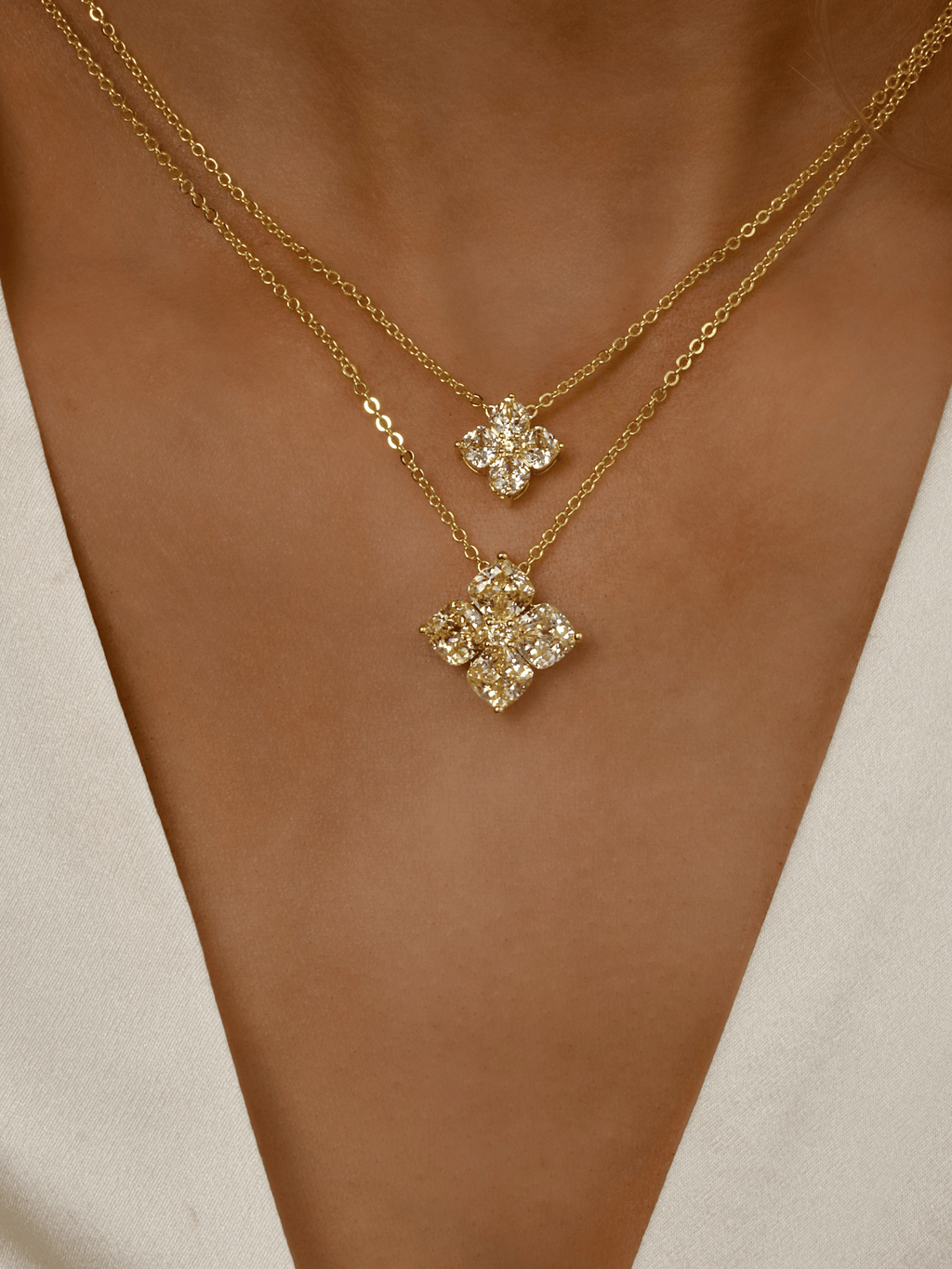 Model wearing stacked Gold Crystal Hydrangea Necklace and Mini Crystal Hydrangea Necklace in Lemon Drop, showing layered CZ floral pendants on the neckline
