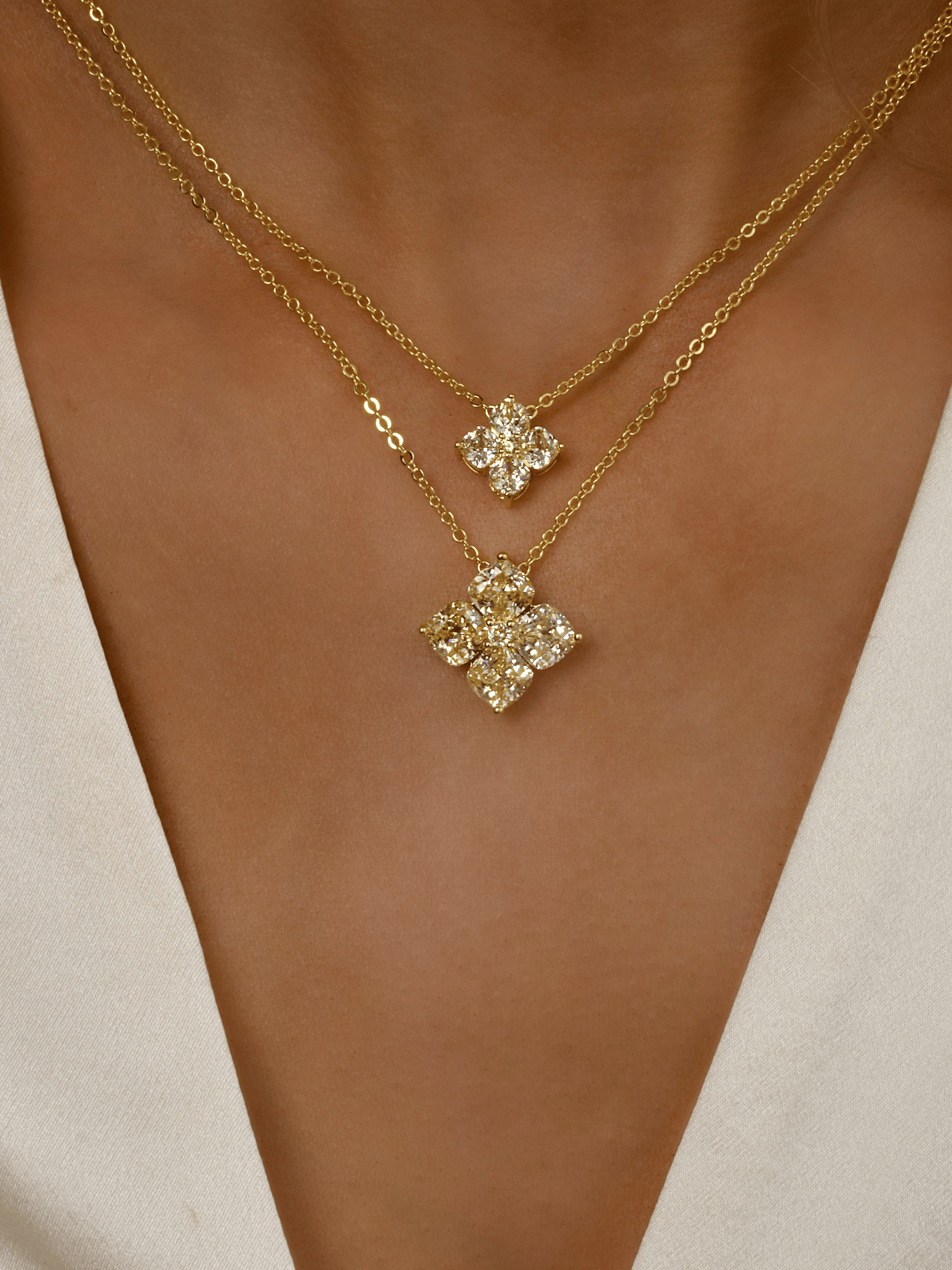 Model wearing stacked Gold Crystal Hydrangea Necklace and Mini Crystal Hydrangea Necklace in Lemon Drop, showing layered CZ floral pendants on the neckline
