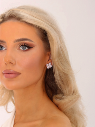 Diagonal portrait of blonde model wearing Sterling Silver Hydrangea CZ stud earrings with White Gold plated floral design complementing natural makeup.