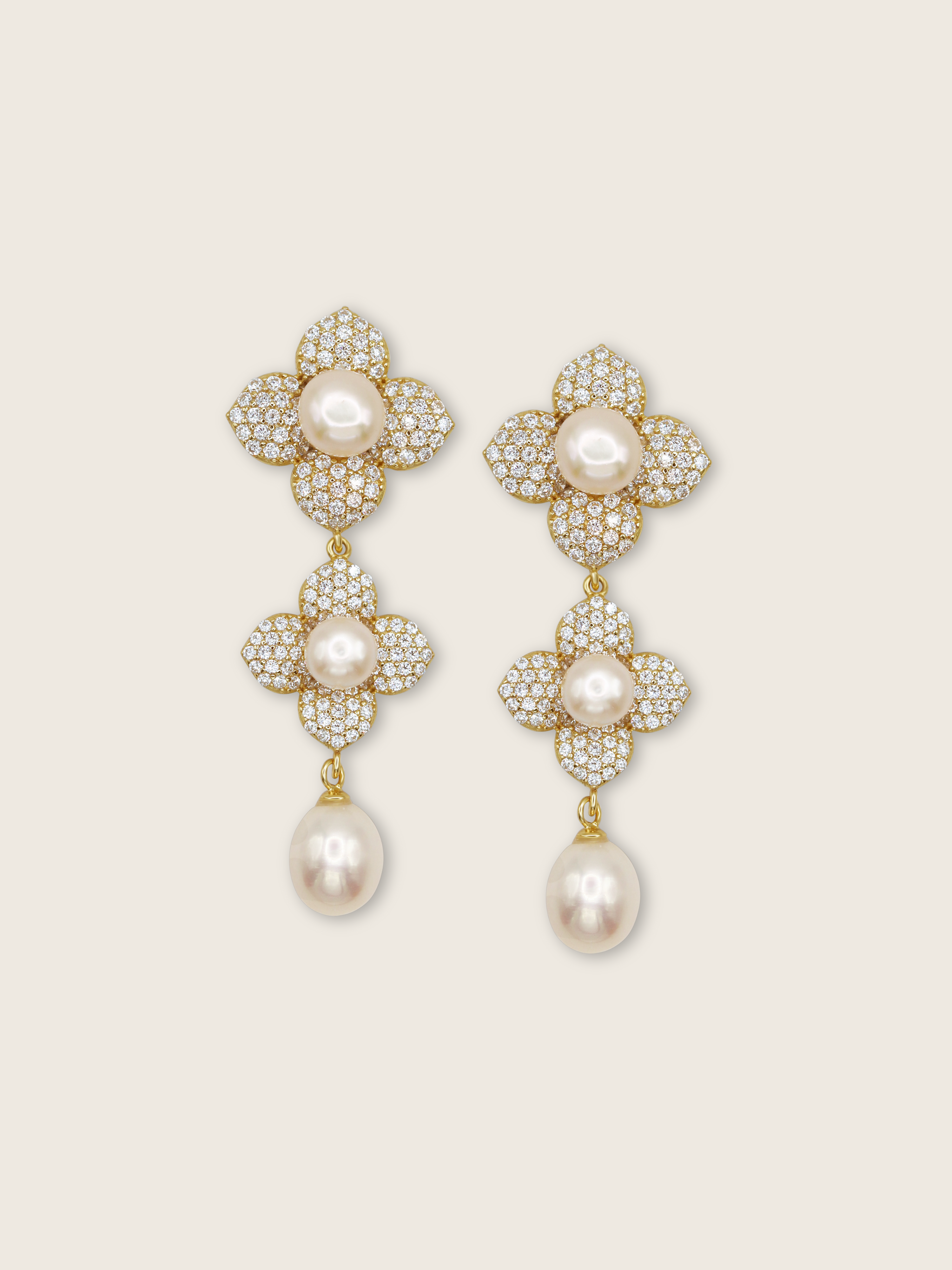 Triple flower drop earrings with freshwater pearls and CZ stones in 14k gold plating on a cream background