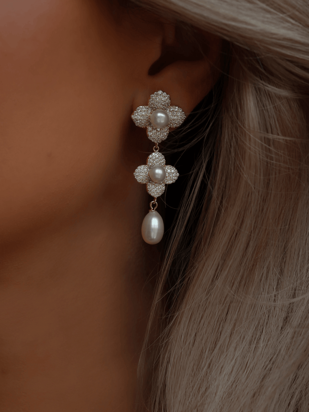 Model wearing 14k gold plated floral drop earrings with freshwater pearls and pavé CZ detailing