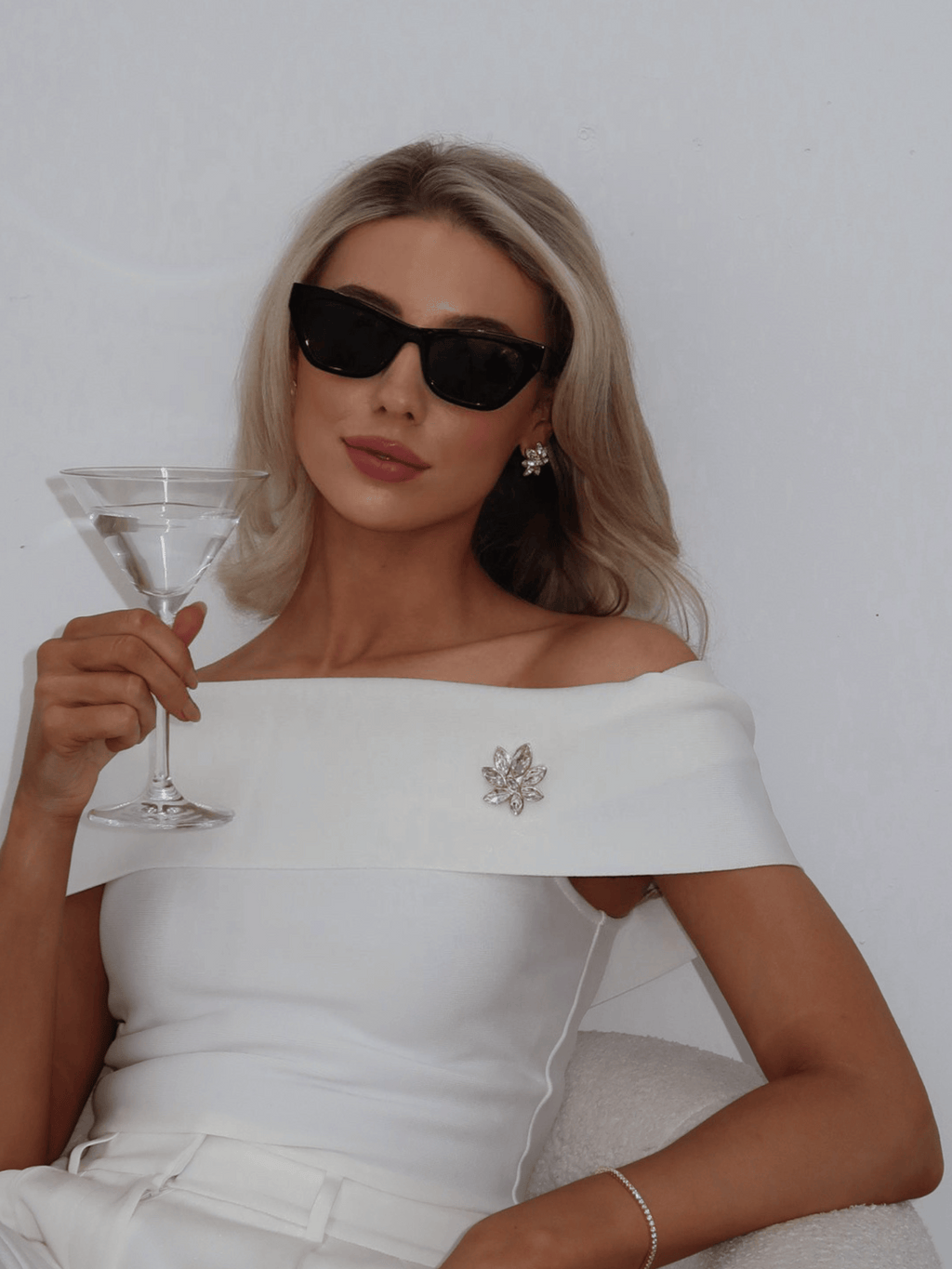 Model wearing Iris Brooch in 14k gold plating with clear marquise cut cubic zirconia stones on off shoulder dress paired with matching Iris Earrings