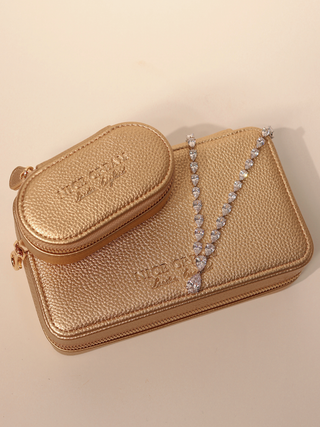Large and small champagne jewellery cases stacked with a crystal necklace draped across the cases.