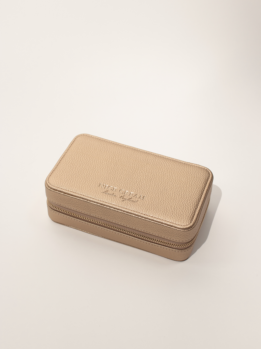 Large champagne jewellery case closed with embossed Nice Cream London logo and gold zip.