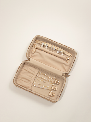 Large champagne jewellery case open with earring strap, zipped pocket, bracelet holders and a selection of jewellery displayed inside.