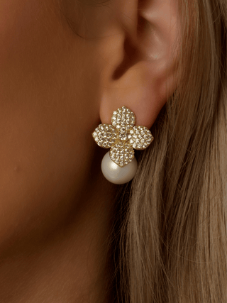 Close-up of model wearing Lemon Drop Hydrangea earrings in gold plating, with lemon CZ stones and a dangling shell pearl beneath the flower