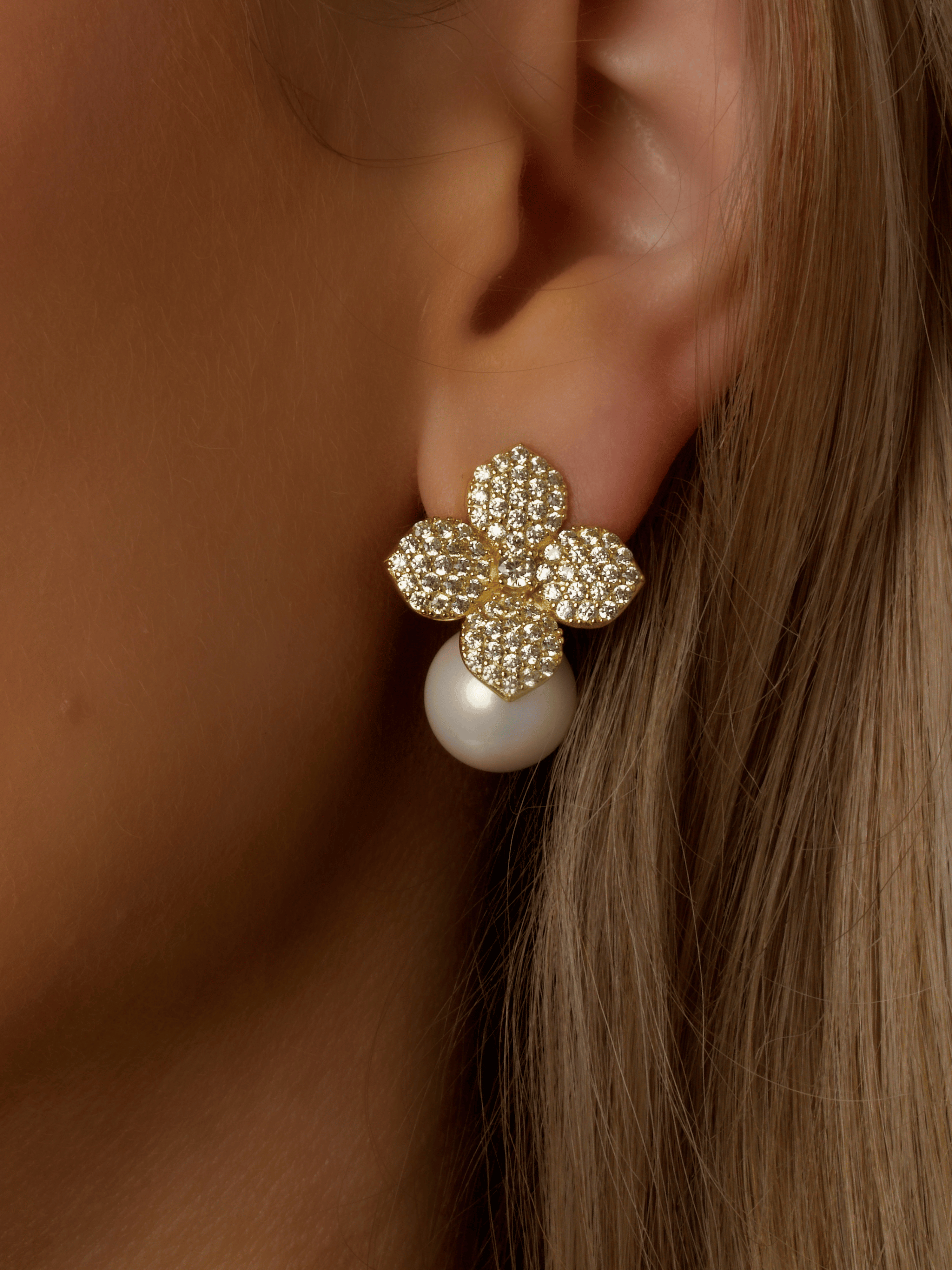 Close-up of model wearing Lemon Drop Hydrangea earrings in gold plating, with lemon CZ stones and a dangling shell pearl beneath the flower