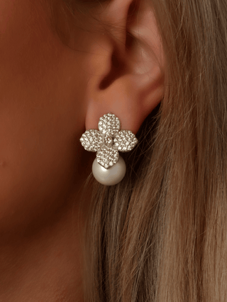 Close-up of model wearing Lemon Drop Hydrangea earrings in white gold, featuring lemon CZ stones in a floral design with a shell pearl drop