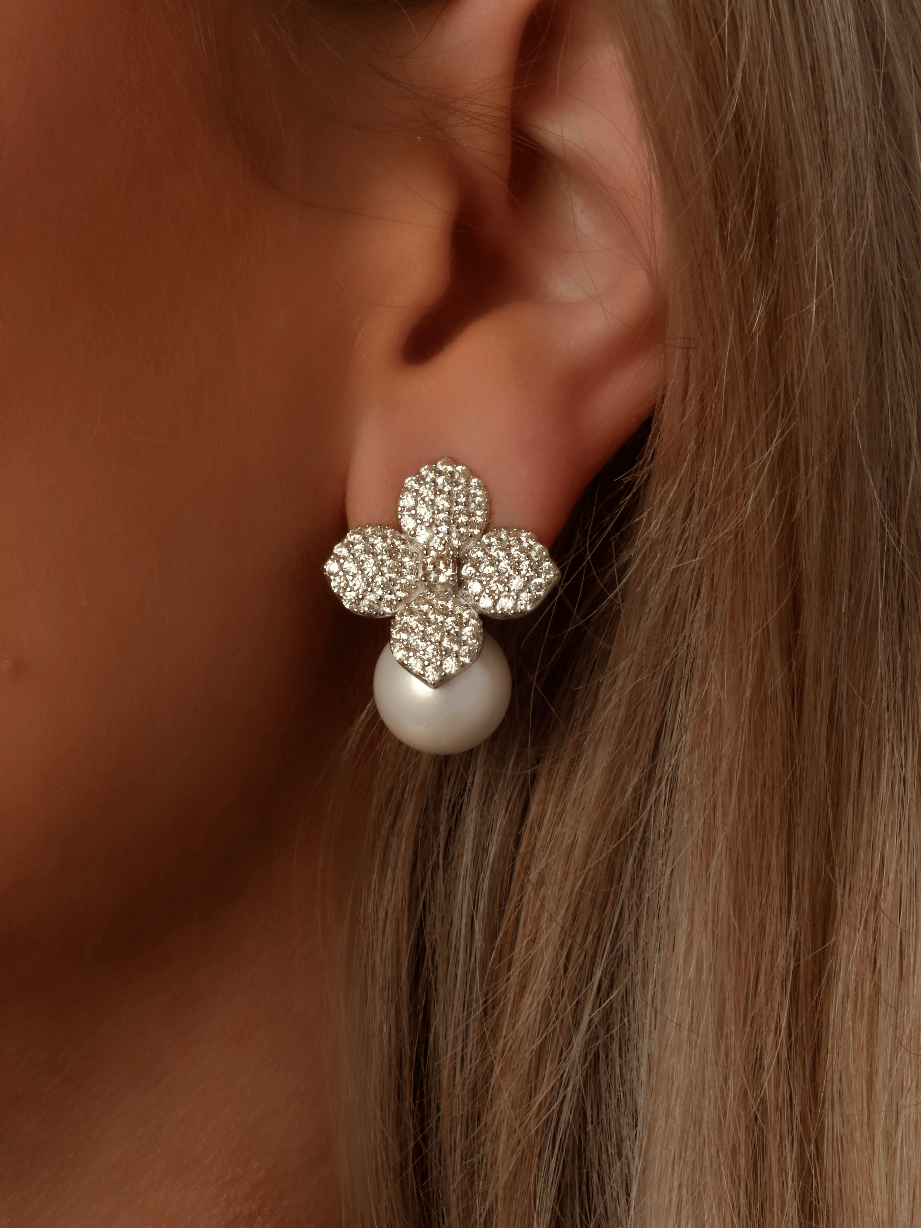 Close-up of model wearing Lemon Drop Hydrangea earrings in white gold, featuring lemon CZ stones in a floral design with a shell pearl drop