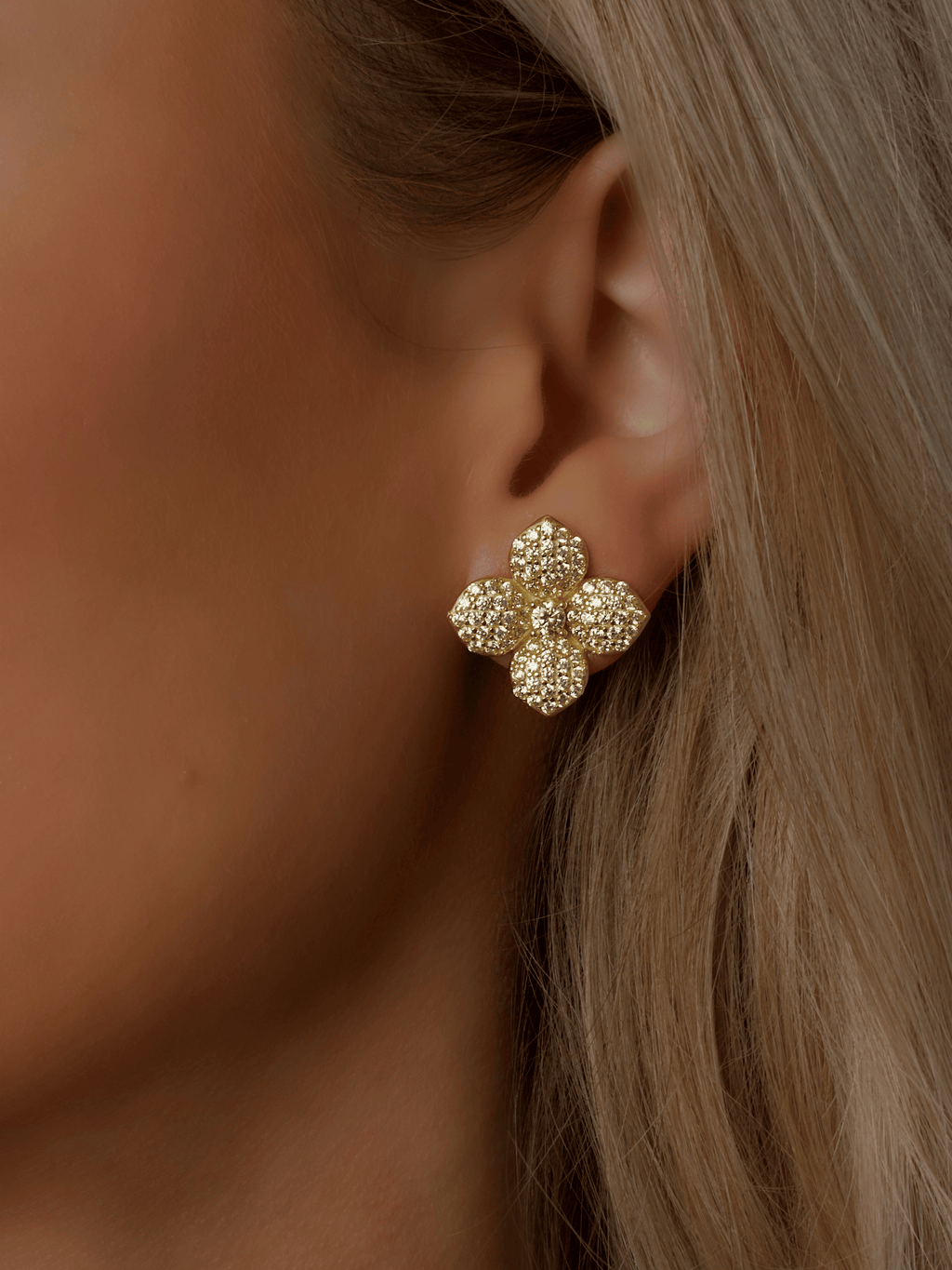 Lemon Drop Hydrangea stud earrings in a model's ear with 14k Gold plating, detailed with lemon CZ stones in a symmetrical flower shape