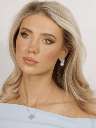 Model showcasing light blue crystal hydrangea earrings with pearl and matching white gold plated necklace