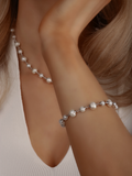 Close-up of White Gold-plated Margot bracelet with freshwater pearls, styled with matching pearl necklace on model in white top