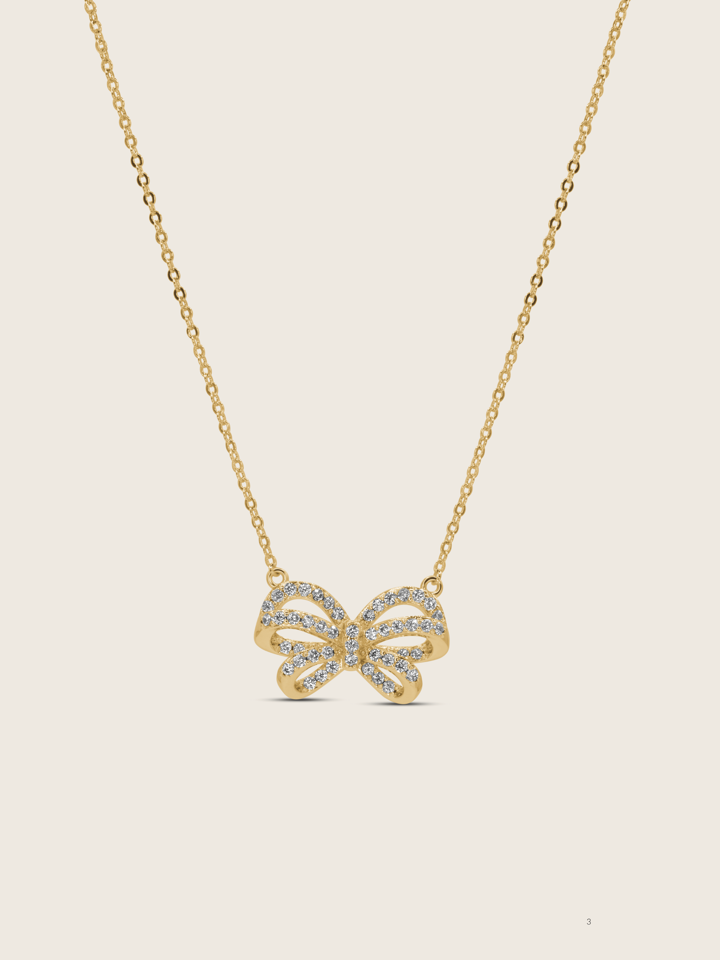 Meredith Bow Necklace in 14k gold plating with crystal pavé bow on fine chain, displayed on neutral background
