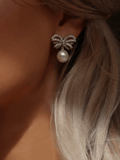 Close-up of white gold bow earrings with CZ stones and shell pearl
