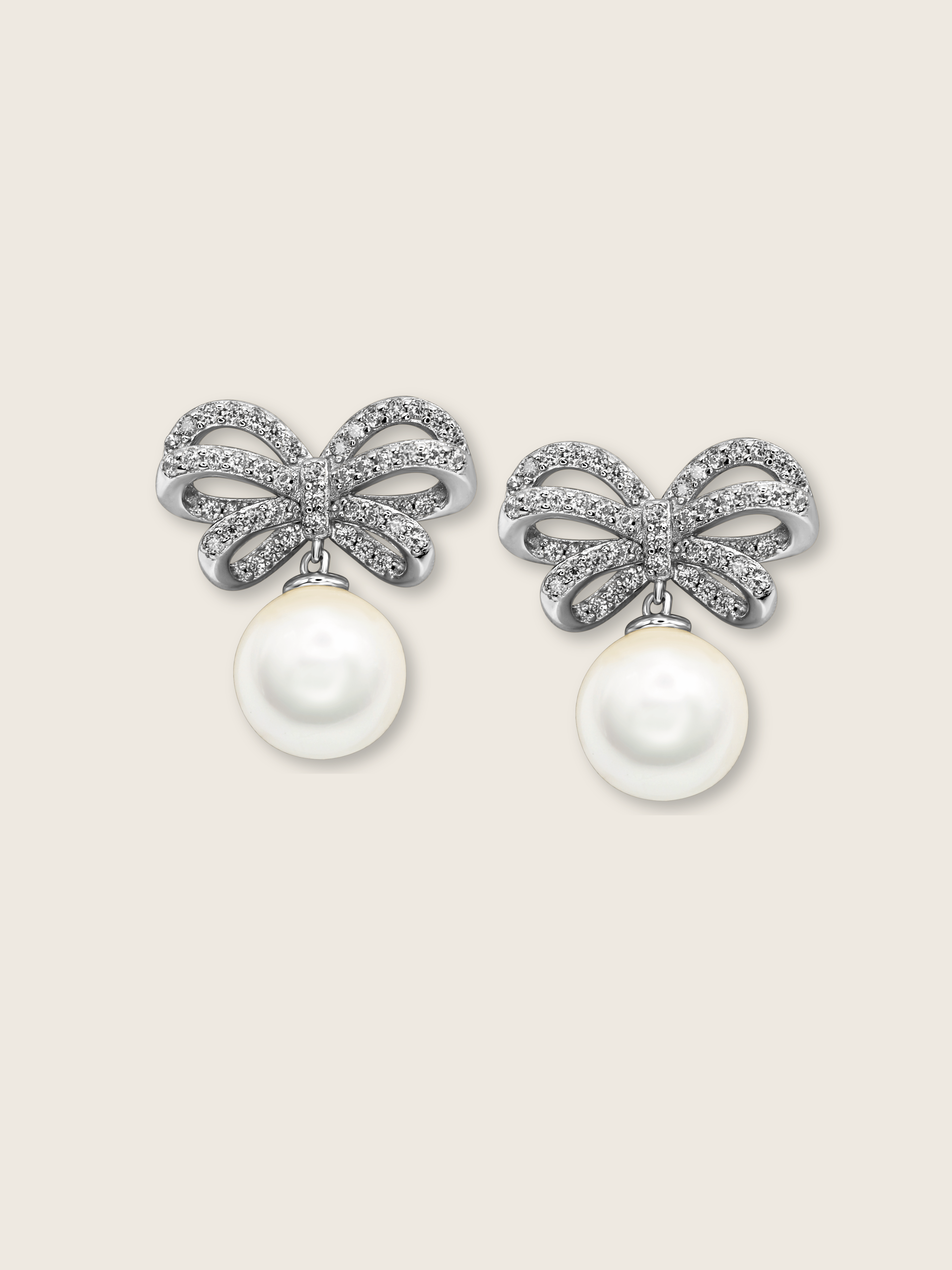 White background product image of white gold bow earrings with shell pearl drop